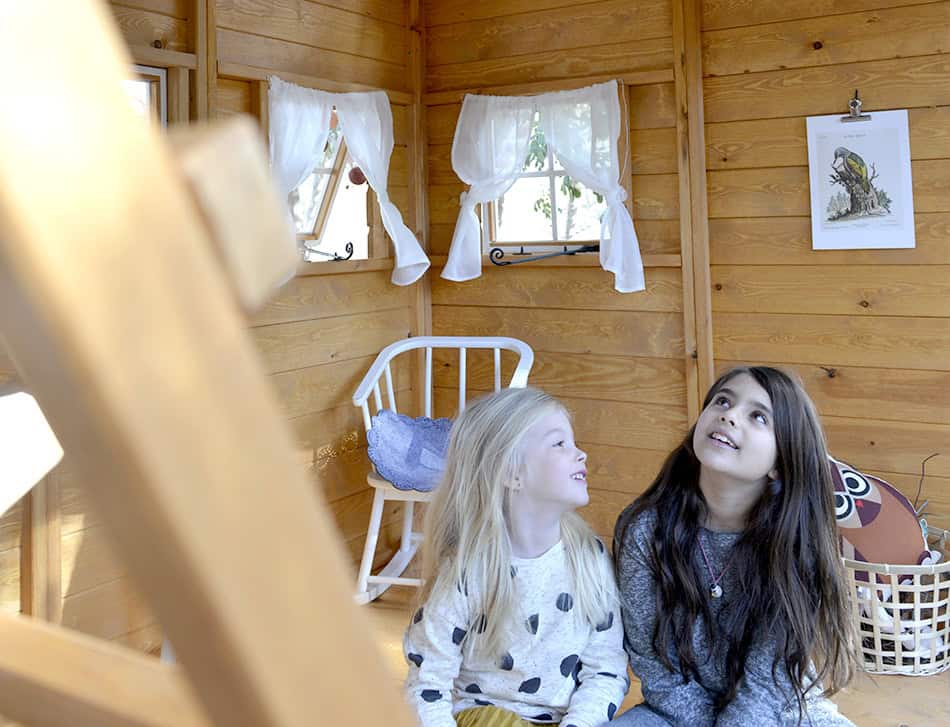 Kinder spielen in einer holzernen Spielhütte im Freien