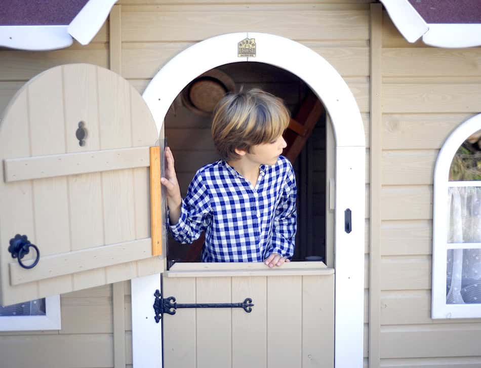 Kinder spielen in einer holzernen Spielhütte im Freien