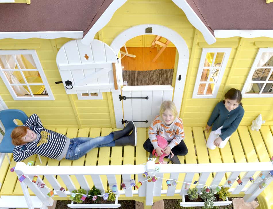 Kinder spielen in einer holzernen Spielhütte im Freien