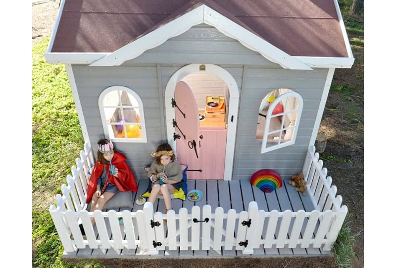 Kinder spielen in einer holzernen Spielhütte im Freien