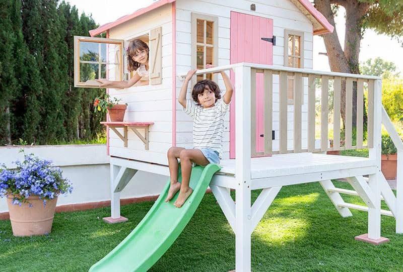 Bambini che giocano in una casetta di legno all'aperto