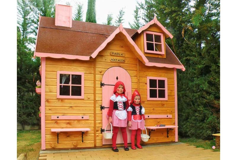 Crianças brincando em uma casinha de madeira ao ar livre