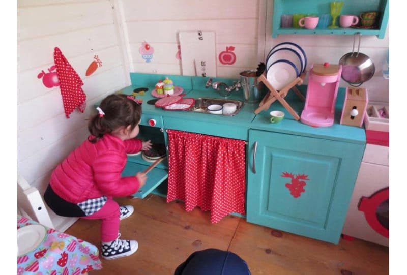 Crianças brincando em uma casinha de madeira ao ar livre