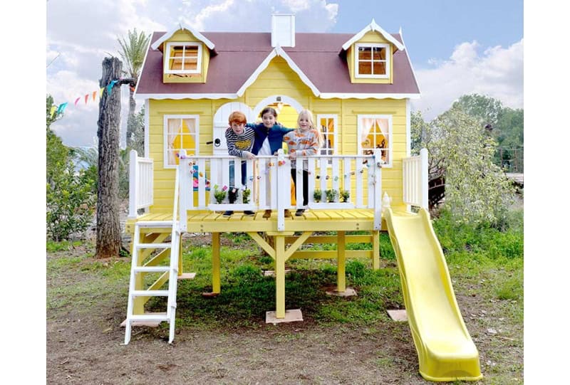 Crianças brincando em uma casinha de madeira ao ar livre