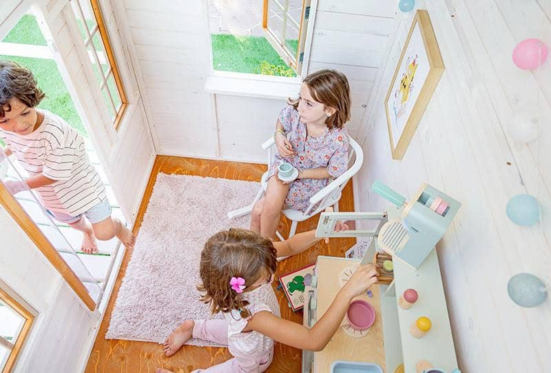 Crianças brincando em uma casinha de madeira ao ar livre