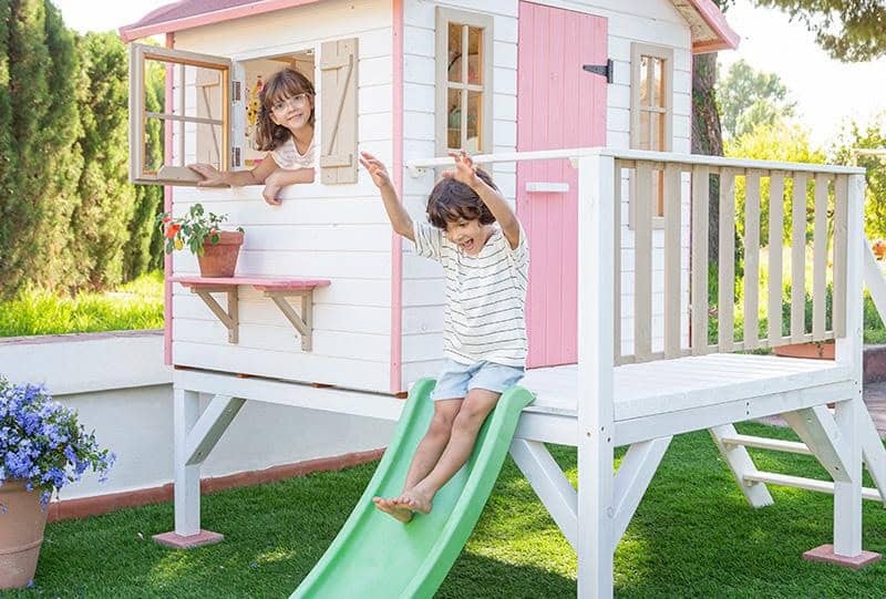 Crianças brincando em uma casinha de madeira ao ar livre