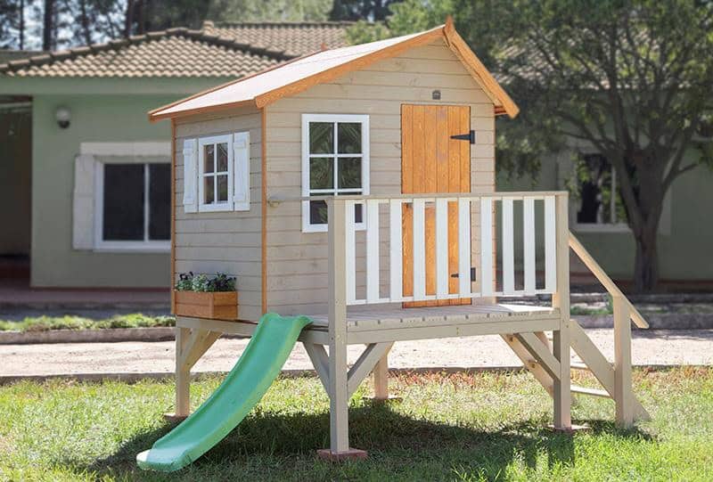 Crianças brincando em uma casinha de madeira ao ar livre