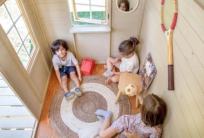 Crianças brincando em uma casinha de madeira ao ar livre