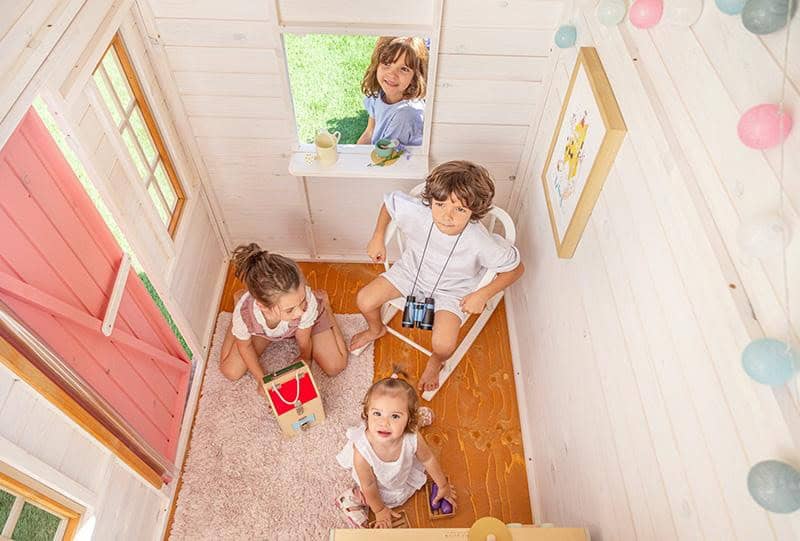 Crianças brincando em uma casinha de madeira ao ar livre