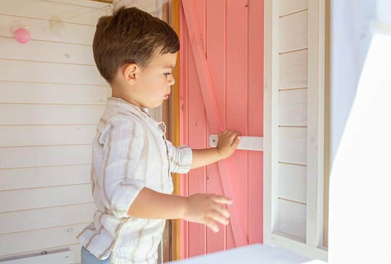 Crianças brincando em uma casinha de madeira ao ar livre