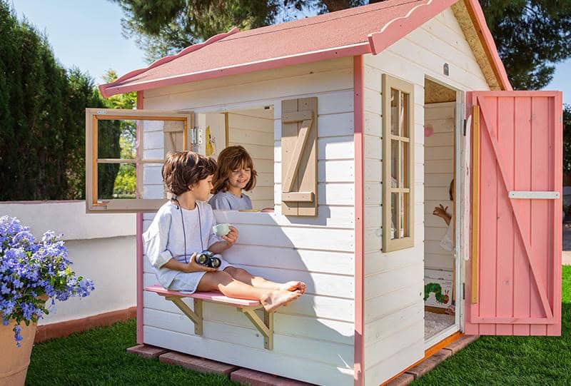 Crianças brincando em uma casinha de madeira ao ar livre