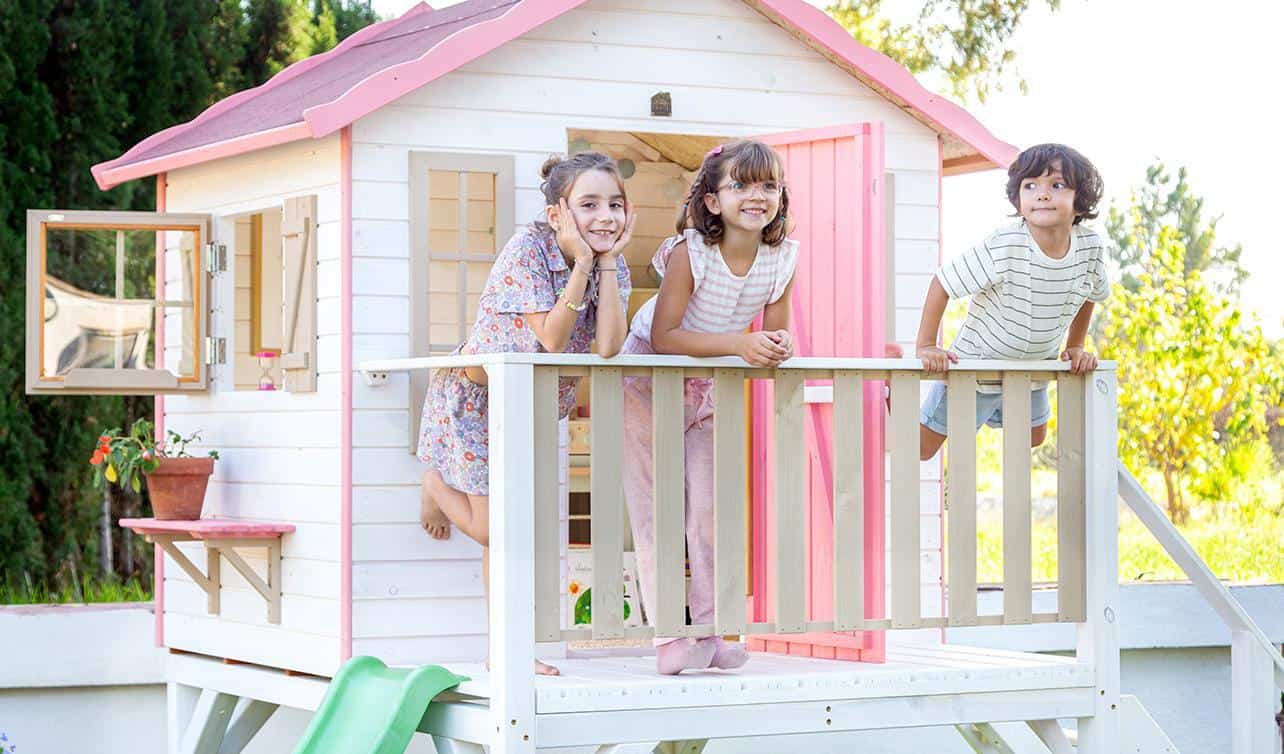 Crianças brincando em uma casinha de madeira ao ar livre
