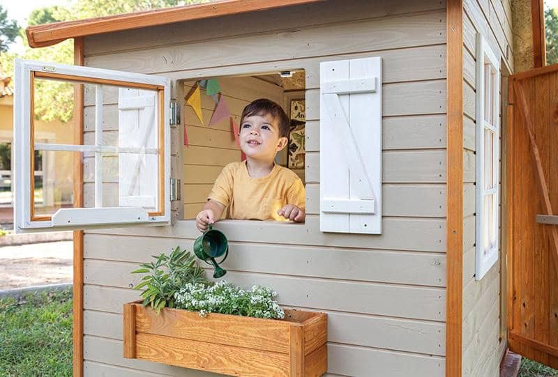 Crianças brincando em uma casinha de madeira ao ar livre